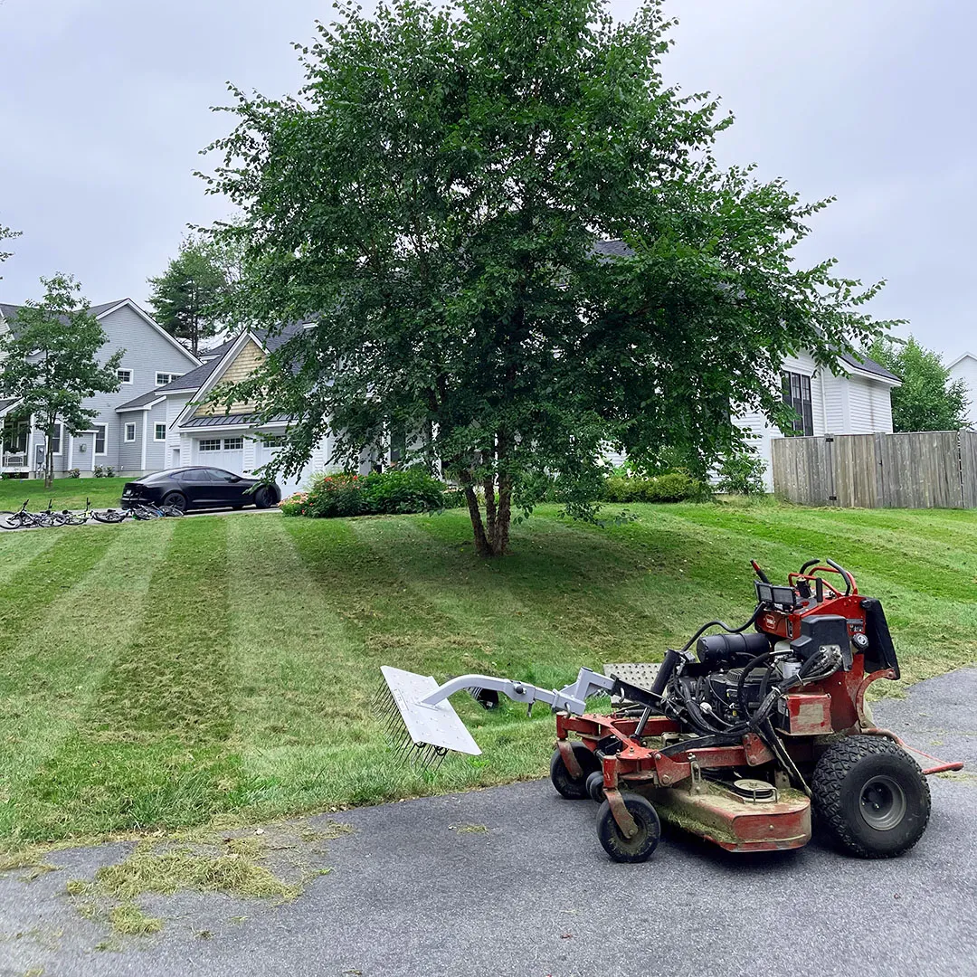 A picture of a lawn mower with a lawn aerator and dethatcher attachment doing lawn dethatching near me
